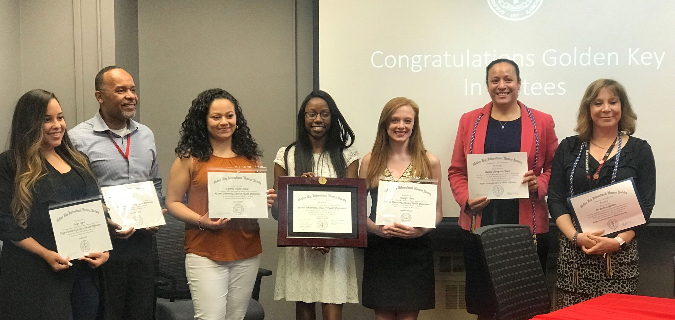 Golden Key Honor Society members holding up their certificates at their induction ceremony