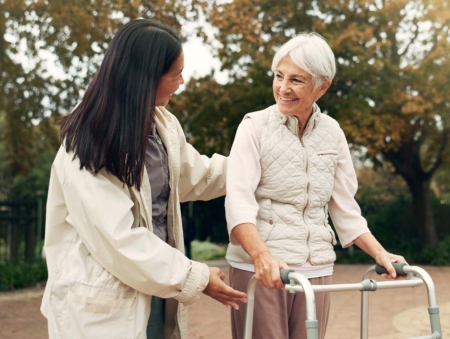 Park, walker and woman help senior walking as support, trust and care for morning healthcare exercise or workout. Health, physical therapy and elderly with caregiver for outdoor rehabilitation