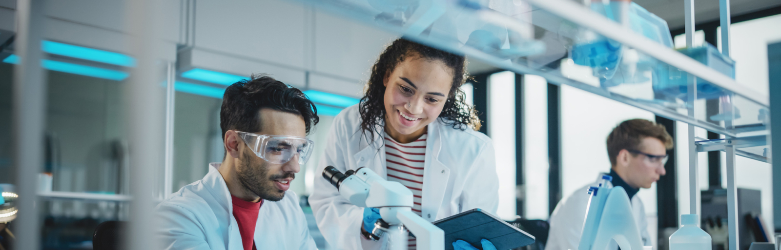 Modern Medical Research Laboratory: Portrait of Latin and Black Young Scientists Using Microscope, Digital Tablet, Doing Sample Analysis, Talking. Diverse Team of Specialists work in Advanced Lab